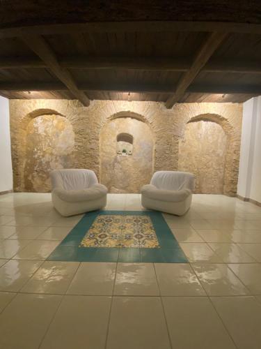 two white chairs and a rug in a room with a wall at La Locanda del Curato Rooms in Lentiscosa