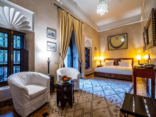 a bedroom with a bed and two chairs and a table at Dar Les Cigognes in Marrakech