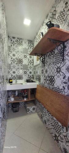 La salle de bains est pourvue d'un lavabo et de papier peint à fleurs. dans l'établissement Apartamentos da Gaby, à Morro de São Paulo