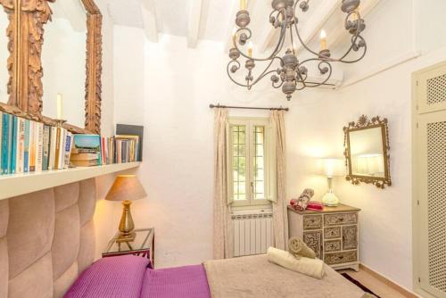 una camera con letto viola e lampadario pendente di Can Bet a Cala Llonga