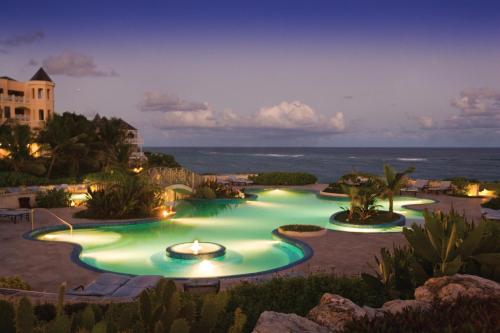 a pool at a resort with the ocean in the background at The Crane Resort in Saint Philip