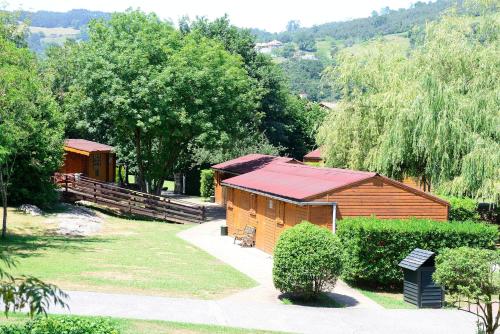 a wooden cabin with a red roof in a park at Albergue Finca El Mazo in Rada