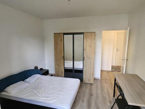 une chambre avec un lit, un bureau et une table dans l'établissement Appartement lumineux avec jardin et terrasse proche stade JO, à Bois-Colombes