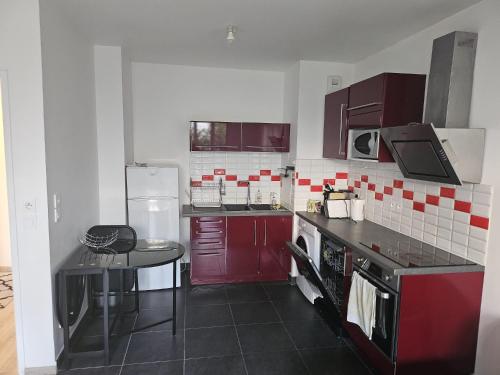 - une cuisine avec des placards rouges et une table dans l'établissement Appartement lumineux avec jardin et terrasse proche stade JO, à Bois-Colombes