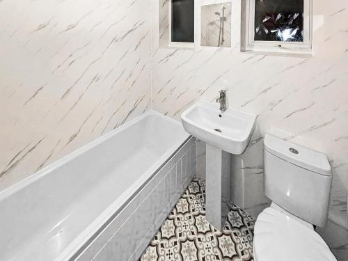 a white bathroom with a sink and a toilet and a tub at Coastal Hideout in Wells next the Sea