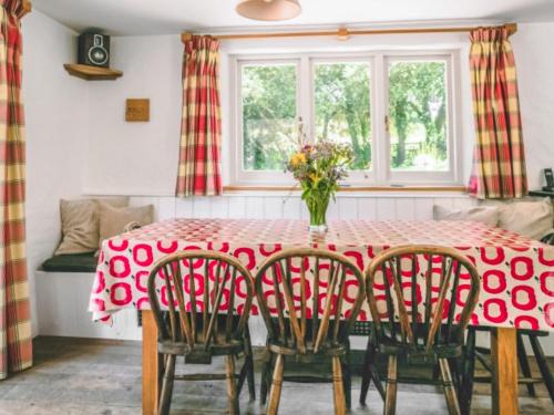 una mesa roja con sillas y un jarrón de flores en Shute Cottage, en Manorbier