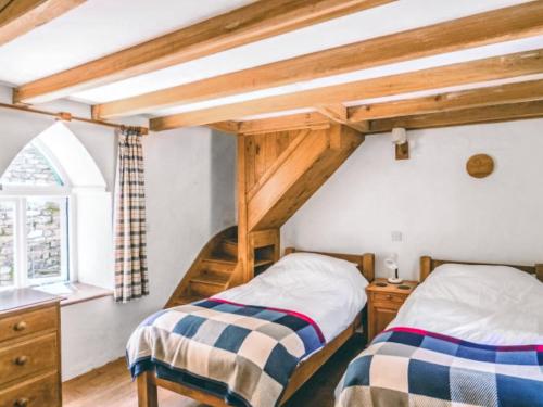 2 camas en un dormitorio ático con vigas de madera en Shute Cottage, en Manorbier