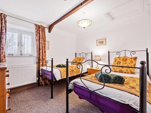 2 camas en un dormitorio con paredes blancas en The Cottage, en South Barrow