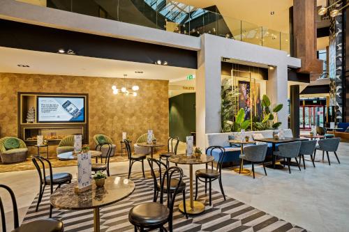 een restaurant met tafels en stoelen in een gebouw bij Corendon Amsterdam Schiphol Airport, a Tribute Portfolio Hotel in Badhoevedorp