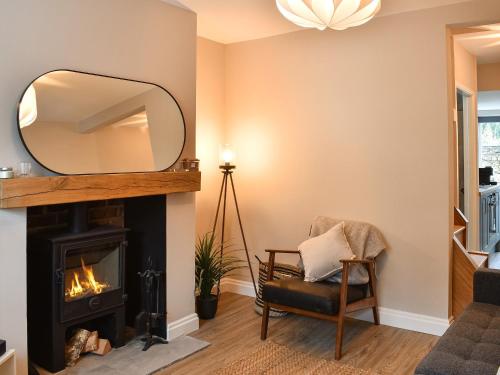 a living room with a fireplace and a mirror at Bramble Cottage in Bramham