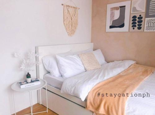 a bedroom with a white bed with a night stand at Korean Themed Condo Staycation in Marilao, Bulacan in Marilao