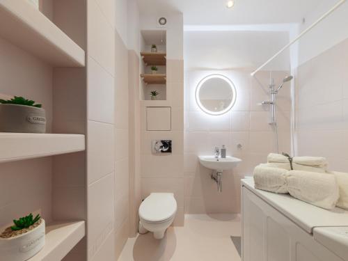 a white bathroom with a toilet and a sink at Bonifraterska Papaya Apartment in Warsaw