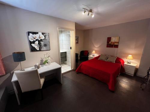 - une chambre avec un lit rouge, une table et un bureau dans l'établissement La Bonne Auberge, à Ségny