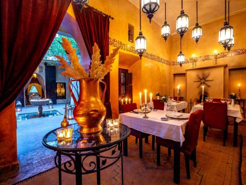 a dining room with a table and a vase with flowers at Dar Les Cigognes in Marrakech