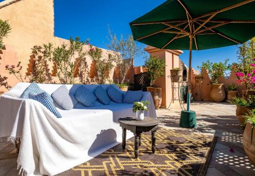 a patio with a couch and an umbrella at Dar Les Cigognes in Marrakech