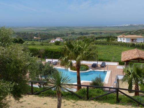 a resort with a swimming pool and palm trees at Hotel Sindhura in Vejer de la Frontera