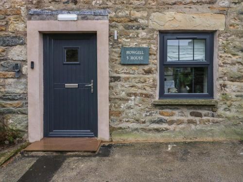 a blue door on a stone building with a window at Howgill House in Sedbergh