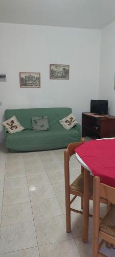 un sofá verde en una sala de estar con mesa en Appartamento Gianna en Alghero
