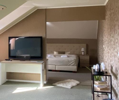 1 dormitorio con 1 cama y mesa con TV en Penzión Aira, en Zvolen