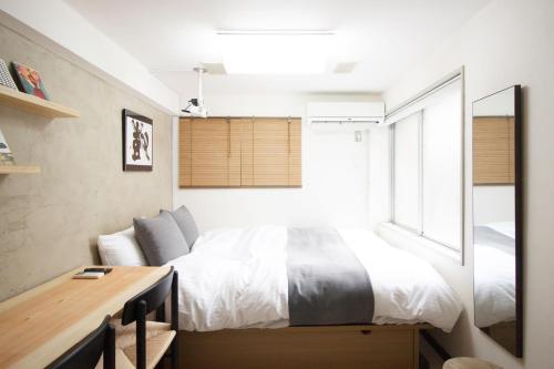 a bedroom with a bed and a desk and a window at Kaku Studio Apartment Ikebukuro in Tokyo