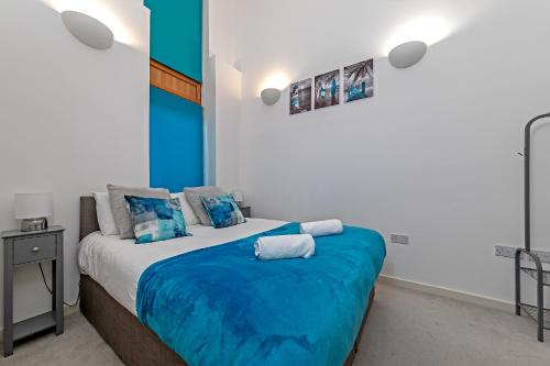 um quarto com uma cama grande e um cobertor azul em Stylish 2 bedroom apartment, 2 bathrooms, free parking for all guest, wifi, Sky, Netflix, walking distance to city centre, sleeps 5, outside patio space, ground floor em Milton Keynes