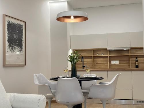 a dining room with a table and white chairs at AIONION RESIDENCES by K&K in Athens