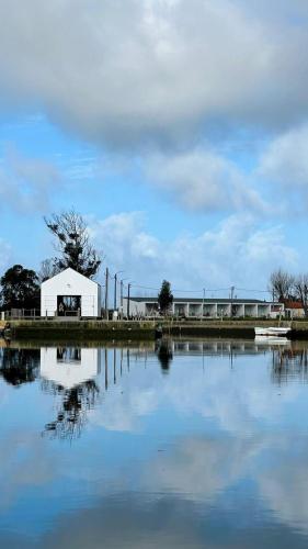 a white barn sitting next to a large body of water at Tijosa Eco-House Camp in Ovar
