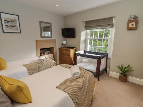 a bedroom with two beds and a desk and a window at Rose Cottage in Matlock