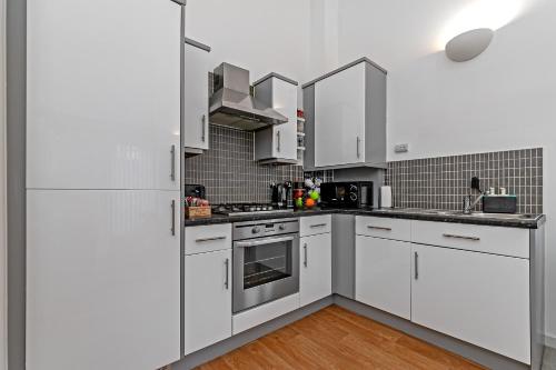 a white kitchen with white cabinets and stainless steel appliances at Stylish 2 bedroom apartment, 2 bathrooms, free parking for all guest, wifi, Sky, Netflix, walking distance to city centre, sleeps 5, outside patio space, ground floor in Milton Keynes