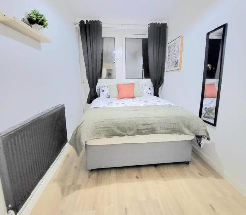 a bedroom with a bed with a pink pillow on it at Three Bed Flat In Mile End in London