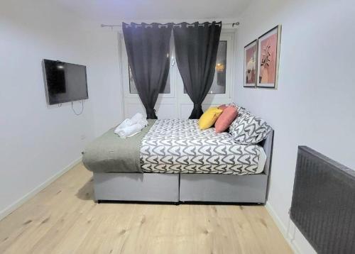 a bedroom with a bed with pillows and a window at Three Bed Flat In Mile End in London