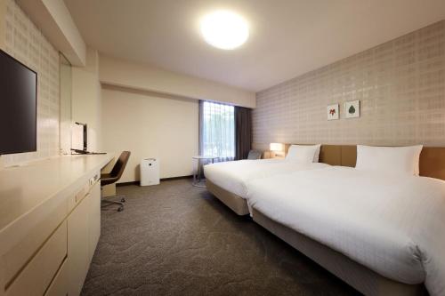 a hotel room with two beds and a flat screen tv at Richmond Hotel Fukushima Ekimae in Fukushima