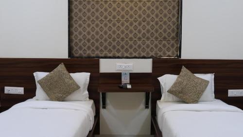 two beds with pillows and a table in a room at Sengar's Inn in Gwalior