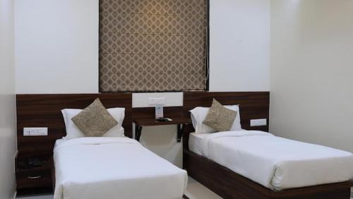 two beds with white sheets in a room at Sengar's Inn in Gwalior
