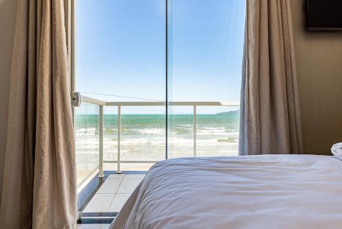 a bedroom with a bed and a view of the ocean at Duplex pé na areia com vista deslumbrante RAT001 in Porto Belo