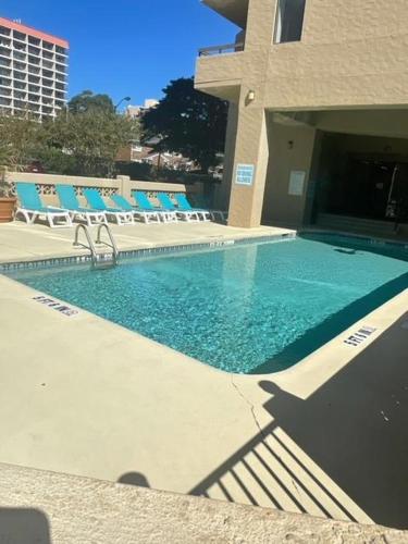 a swimming pool with blue chairs and a building at The Ocean Pearl in Myrtle Beach