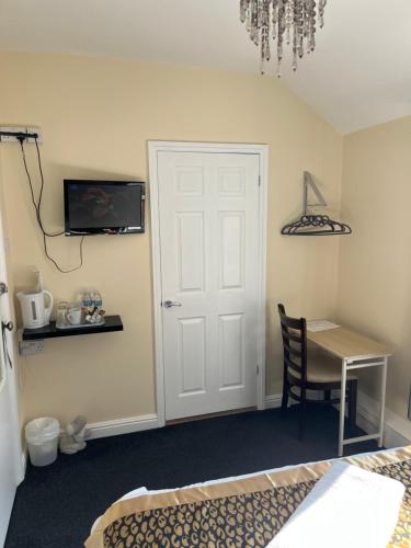 a bedroom with a bed and a desk and a door at The Harp Freehouse and Guesthouse in Ipswich