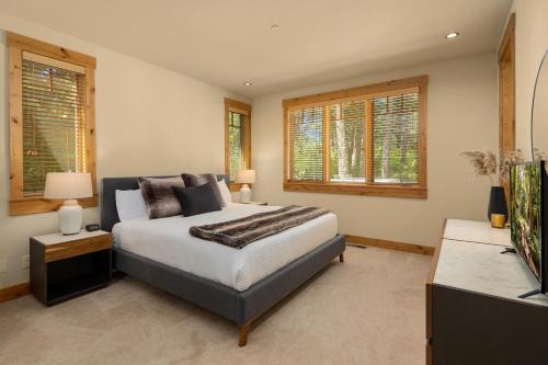 a bedroom with a bed and a tv and windows at All-Season Suncadia Home Hot Tub and Heated Patio in Cle Elum
