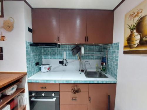 uma cozinha com armários castanhos e um lavatório em Stay in Manila, Cambridge Village em Cainta
