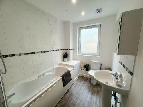 a white bathroom with a tub and a sink at Blueberry Tree Apartment in Cambridge