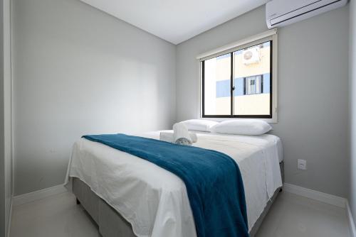 - une chambre blanche dotée d'un lit avec une couverture bleue dans l'établissement Apto aconchegante a 450m do mar EAN503, à Balneário Camboriú