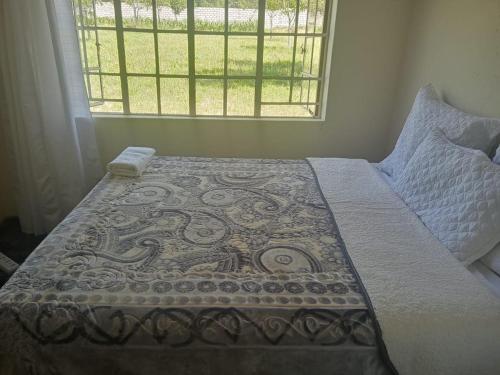 a bed in a bedroom with a window at Two Bed Two Bath Cottage in Bulawayo