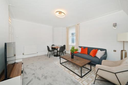 ein Wohnzimmer mit einem blauen Sofa und einem Tisch in der Unterkunft London Choice Apartments - Baker Street- Regent's Park in London