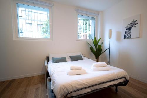 um quarto com uma cama com lençóis brancos e 2 janelas em tHE Urban Wildlife - San Babila Home em Milão
