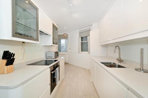 eine weiße Küche mit weißen Schränken und einem Waschbecken in der Unterkunft London Choice Apartments - Baker Street- Regent's Park in London