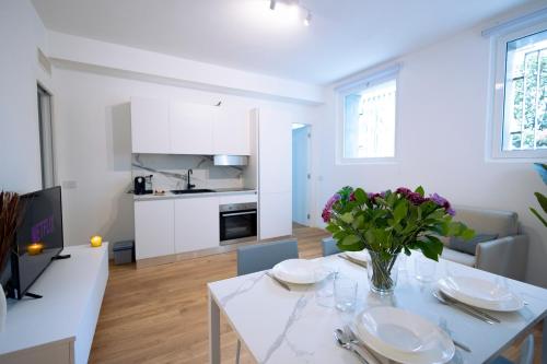 uma cozinha e sala de estar com uma mesa branca com flores em tHE Urban Wildlife - San Babila Home em Milão