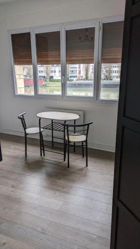 Appartement Creil Centre-ville في كريل: طاولة وكراسي في غرفة بها نوافذ