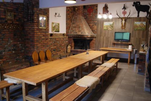 a restaurant with a large wooden table and a fireplace at Pokoje w Moszczenicy U Pasonia in Stary Sącz