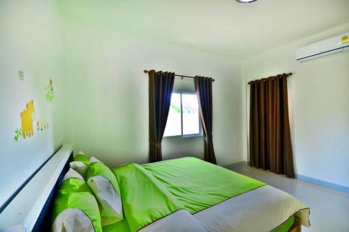 a bedroom with a green bed and a window at The Guestvilla644 in Hua Hin