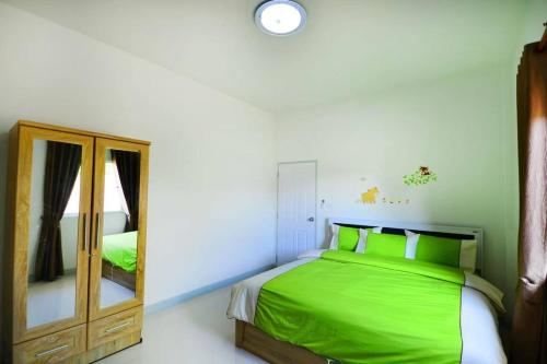 a bedroom with a green bed and a mirror at The Guestvilla644 in Hua Hin